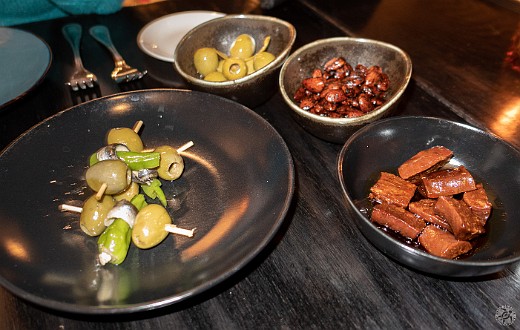 The Essex Spanish Tapas Dinner-004 Clockwise from left: marinated white anchovies, peppers, and olives; lemon-marinated olives; roasted almonds and pimenton; chorizo braised in cider